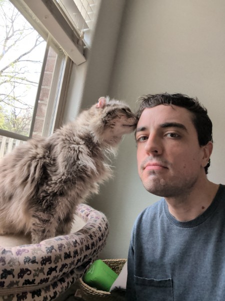 Andrew and Princess the cat sharing a tender head bonk by the window